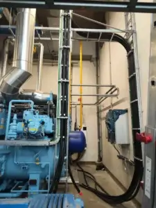 Priemyselné chladiace jednotky s prepojenými rozvodmi, elektrickými káblami a oceľovou infraštruktúrou v technickej miestnosti.