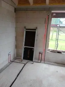 Príprava elektroinštalácie v rodinnom dome, kde sú káble a zásuvky vedené v stenách a podlahe, viditeľné počas výstavby.