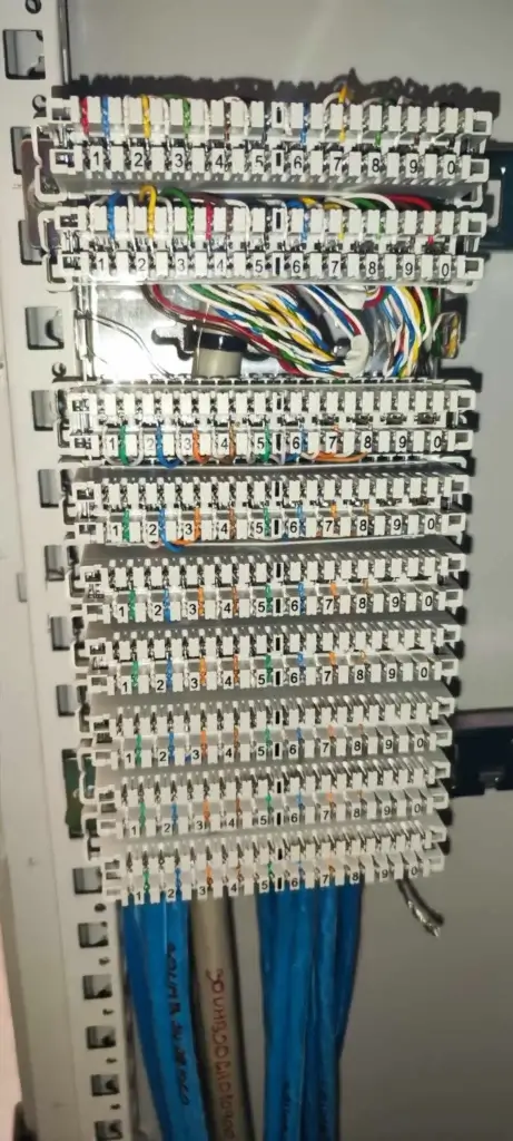 Blízky pohľad na patch panel so zapojenými farebnými Ethernet vodičmi kategórie 6, určený pre dátové siete.