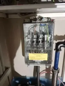 Detailná snímka elektrickej prípojnej skrinky s transparentným krytom, vedením káblov a bezpečnostnými poistkami.