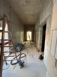 Electrical installation in corridor under construction with visible tools and cables.