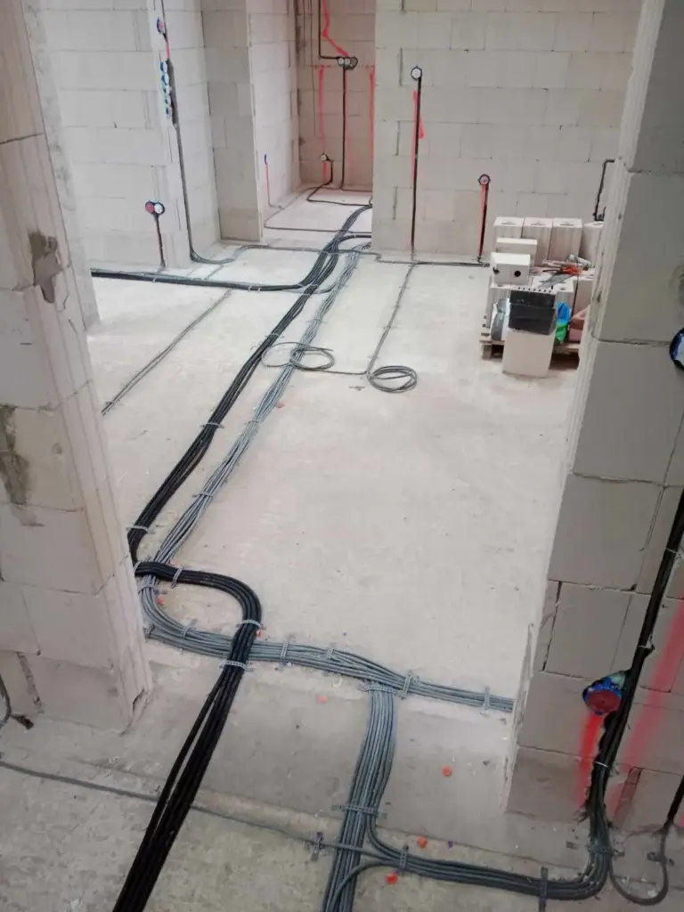 Floor-level electrical conduit installation with precise routing between rooms.