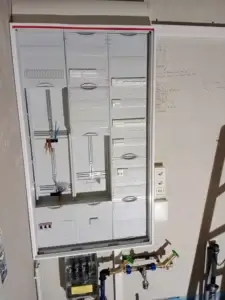 Installed electrical cabinet with plumbing fixtures in a utility room.