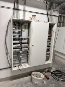 Wall-mounted electrical cabinet during apartment installation, with labeled wiring setup.